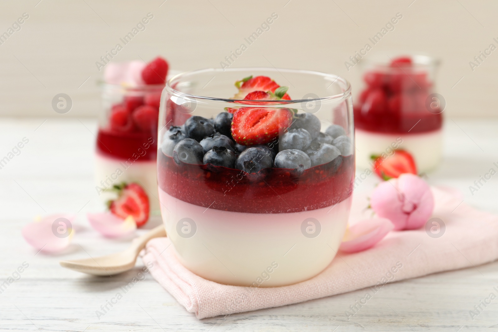 Photo of Delicious panna cotta with berries on white wooden table