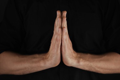 Photo of Man praying against black background, closeup view