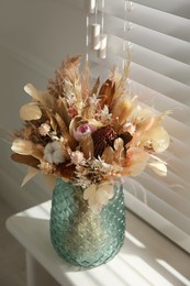 Photo of Beautiful dried flower bouquet in glass vase on white windowsill