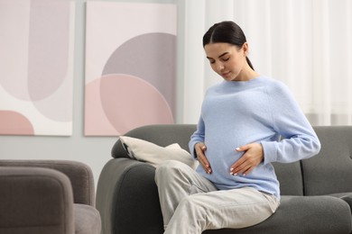 Pregnant young woman on sofa at home