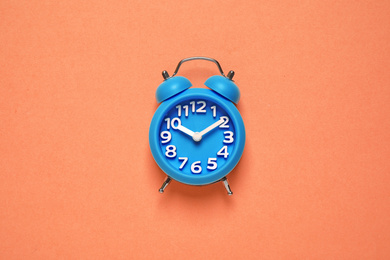 Alarm clock on orange background, top view. Color of the year 2020 (Classic blue)