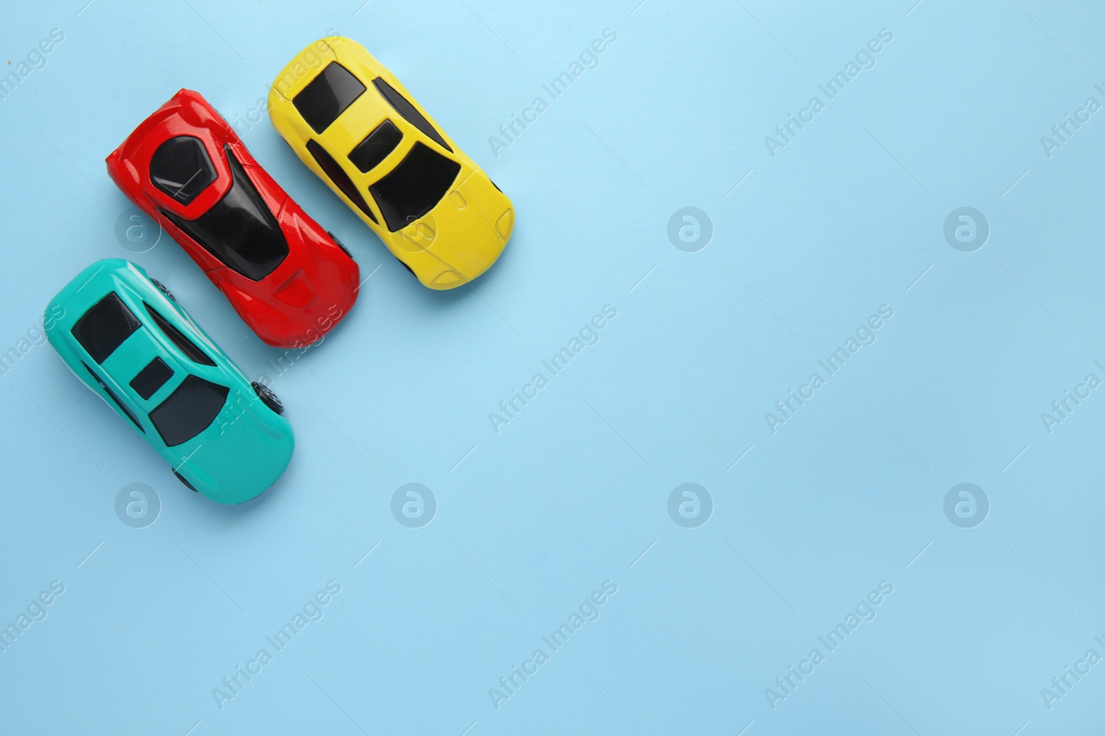 Photo of Different bright cars on light blue background, flat lay with space for text. Children`s toys