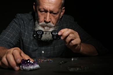 Photo of Male jeweler examining amethyst stone in workshop