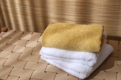 Photo of Stacked soft towels on wicker bench indoors, space for text