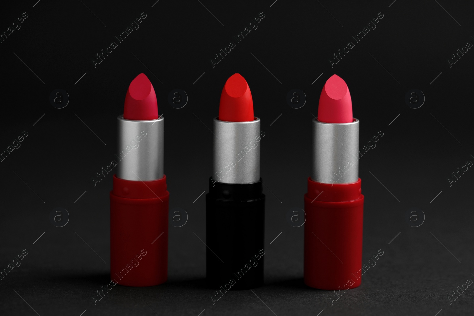 Photo of Different lipsticks on black background. Cosmetic product
