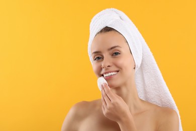 Photo of Smiling woman removing makeup with cotton pad on yellow background. Space for text