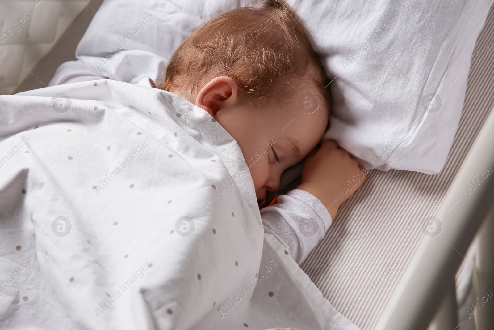 Photo of Cute baby sleeping in crib at home, above view. Bedtime schedule