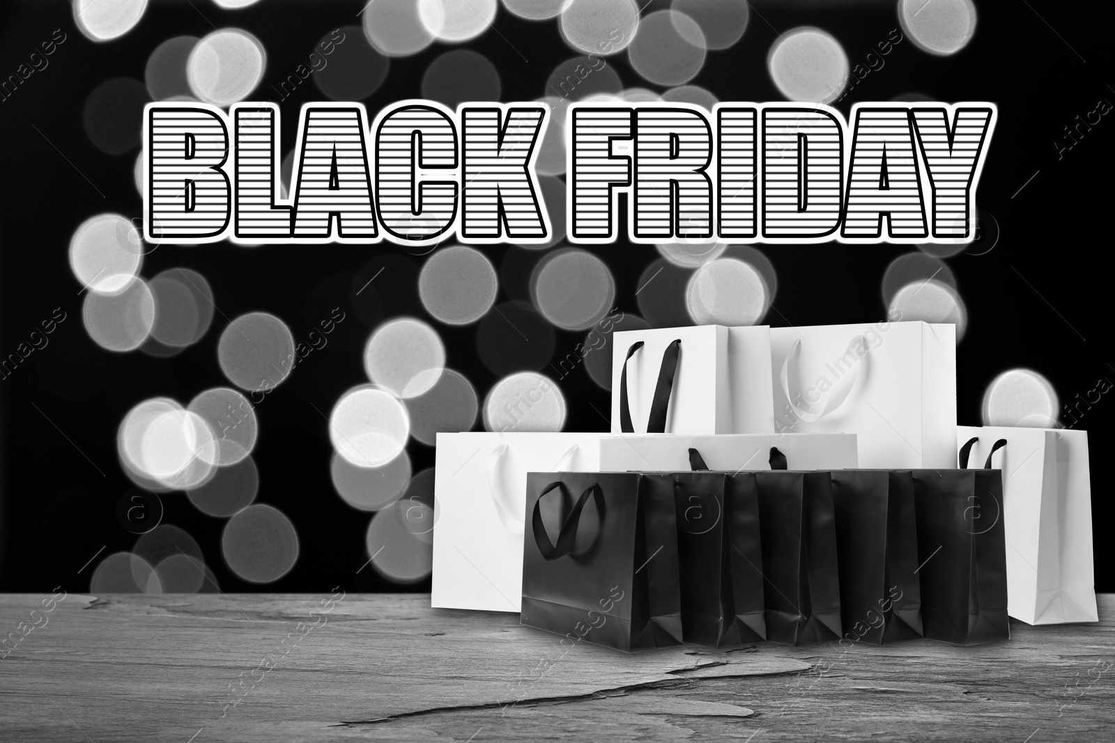 Image of Black Friday. Many shopping bags on table and blurred lights on background