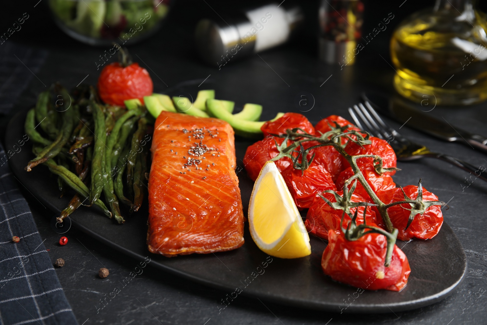 Photo of Tasty cooked salmon and vegetables served on black table. Healthy meals from air fryer