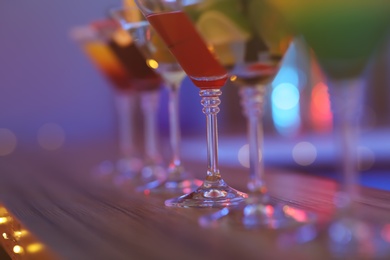 Different martini cocktails on table against blurred background, closeup with space for text