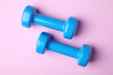 Photo of Bright dumbbells on color background, flat lay. Home fitness