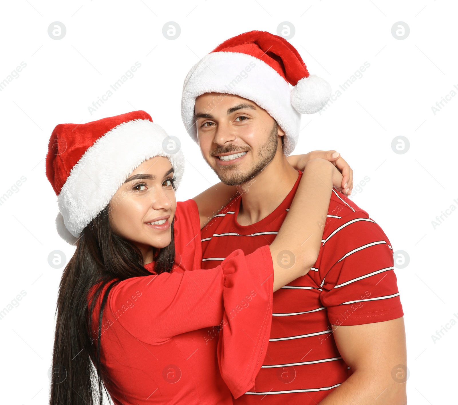 Photo of Young happy couple with Santa hats on white background. Christmas celebration