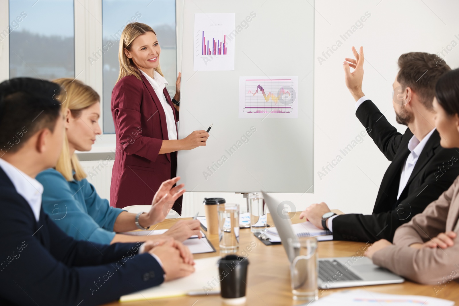 Photo of Businesswoman showing charts near flipchart on meeting in office