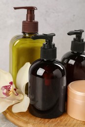 Shampoo bottles, orchid flower and hair mask on light grey table