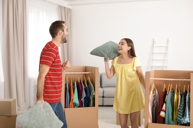 Young couple having pillow fight near wardrobe boxes at home