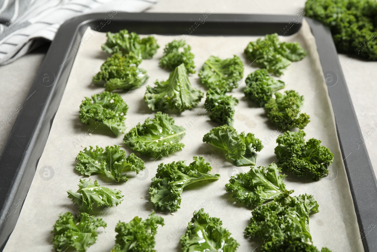 Photo of Raw cabbage leaves on baking sheet, closeup. Preparing kale chips