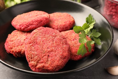 Photo of Delicious beetroot cutlets and parsley in black bowl, closeup. Vegan dish