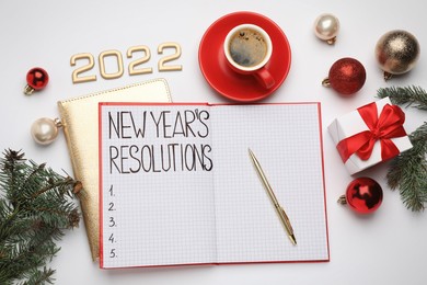 Photo of Making New Year's resolutions. Flat lay composition with notebook, 2022 numbers and festive decor on white background