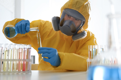 Photo of Scientist in chemical protective suit pouring reagent into test tube at laboratory. Virus research