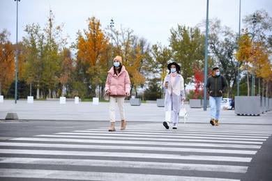 People in medical face masks walking outdoors. Personal protection during COVID-19 pandemic