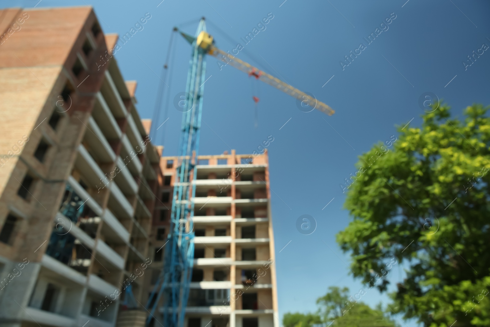 Photo of View of unfinished building and tower crane against blue sky