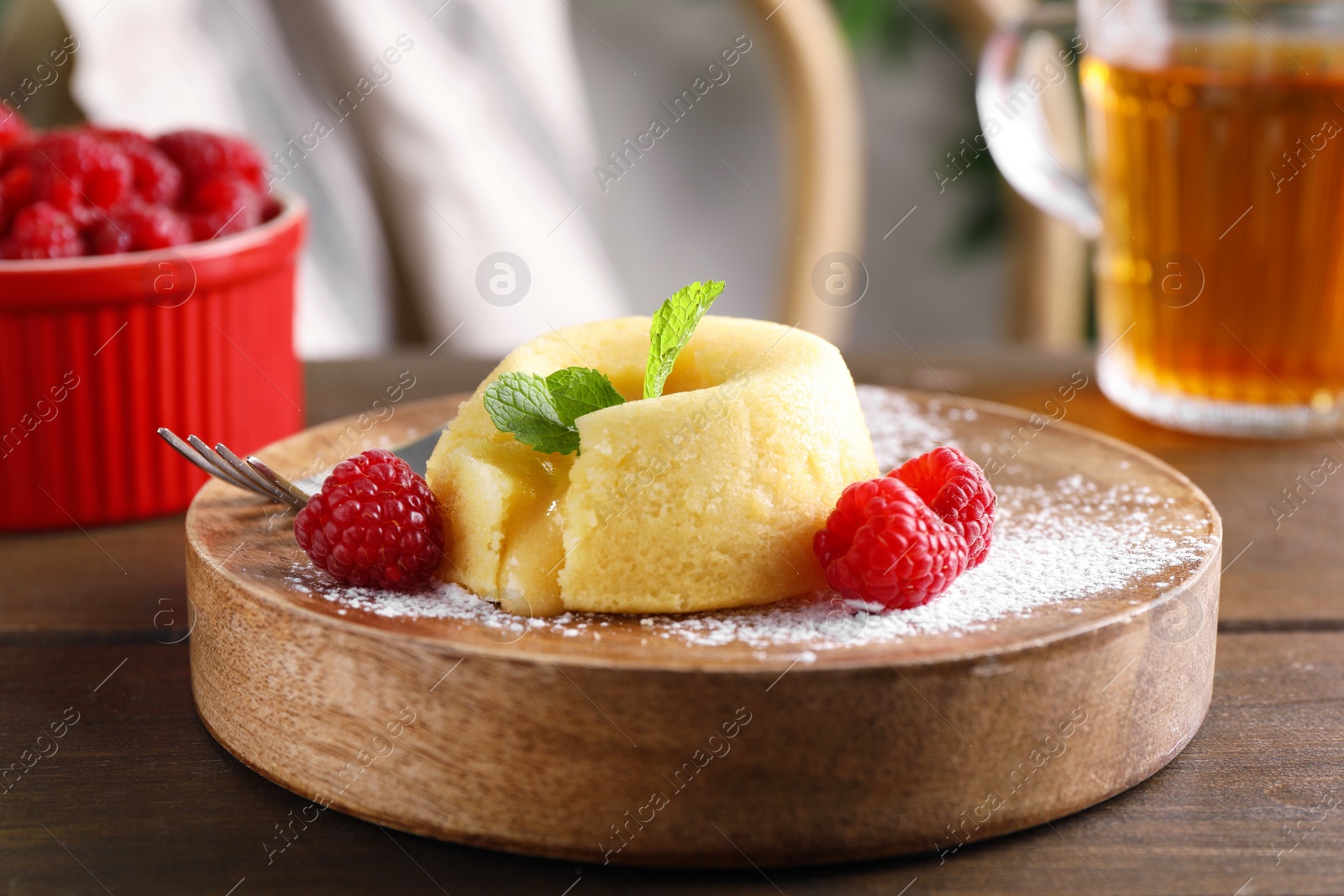 Photo of Tasty vanilla fondant with white chocolate and raspberries on wooden table, closeup
