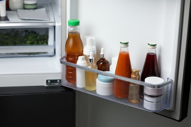 Photo of Different cosmetic products on shelf in refrigerator