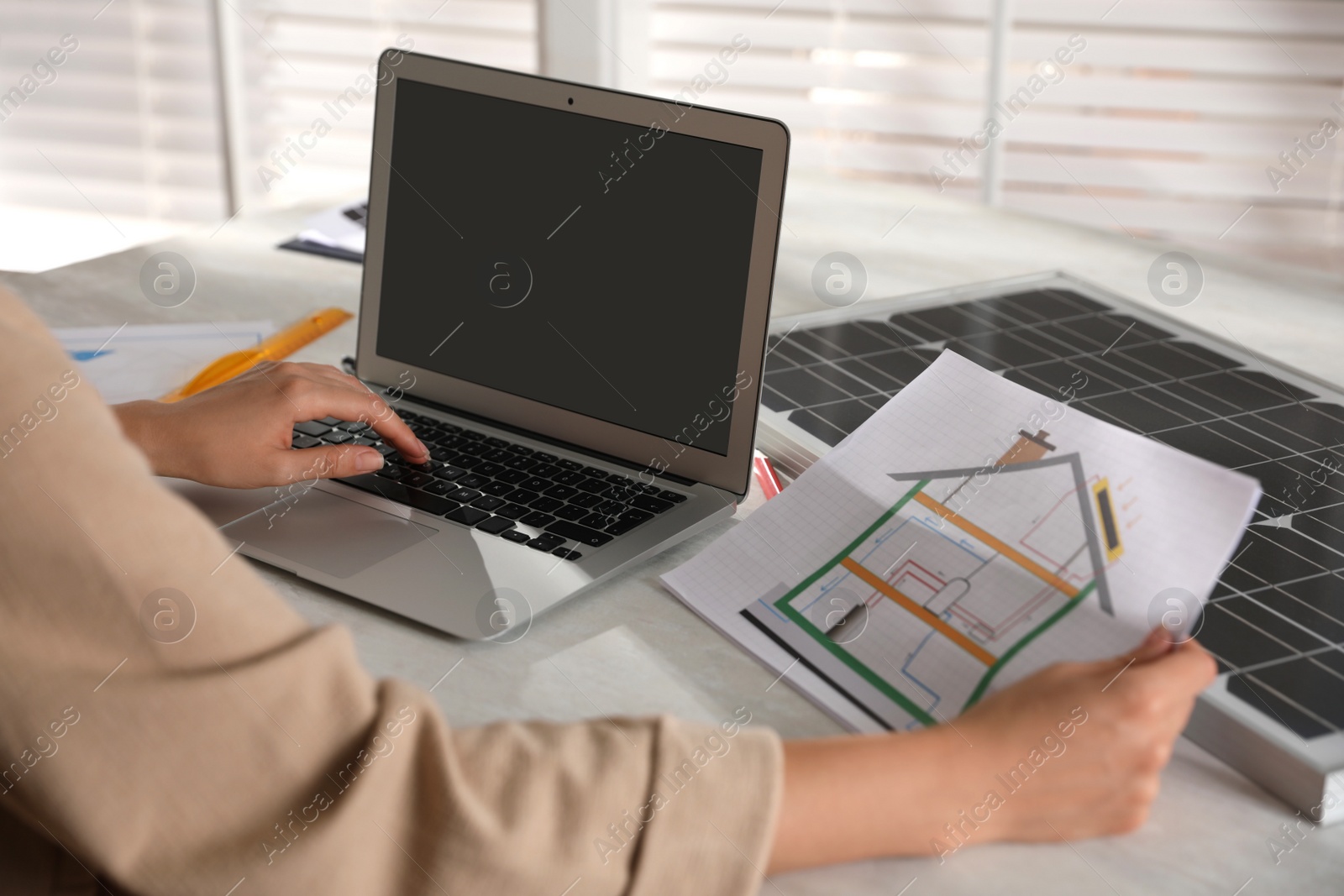 Photo of Woman working on house project with solar panels at table in office, closeup