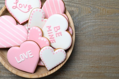 Photo of Valentine's day cookies in bowl on wooden table, top view. Space for text