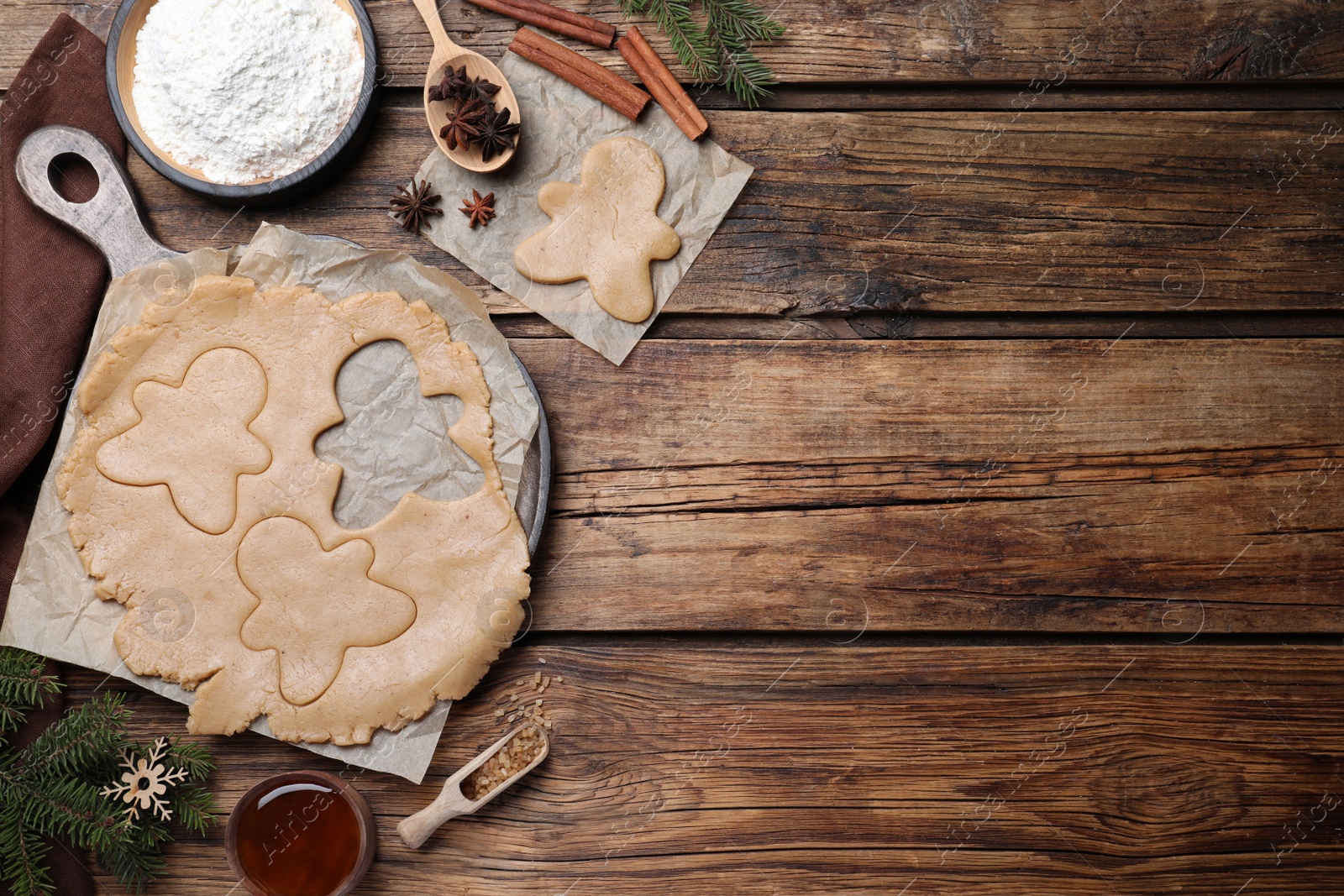 Photo of Flat lay composition with homemade gingerbread man cookies on wooden table, space for text