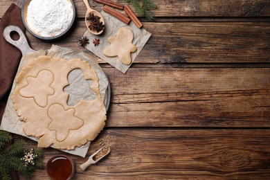 Photo of Flat lay composition with homemade gingerbread man cookies on wooden table, space for text