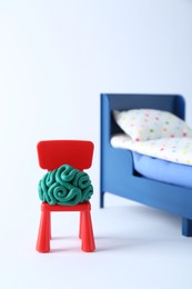 Brain made of plasticine on chair and mini bed against white background