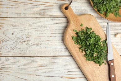 Photo of Board with fresh green parsley and knife on wooden background, top view. Space for text