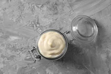 Tasty mayonnaise in jar on gray textured table, top view