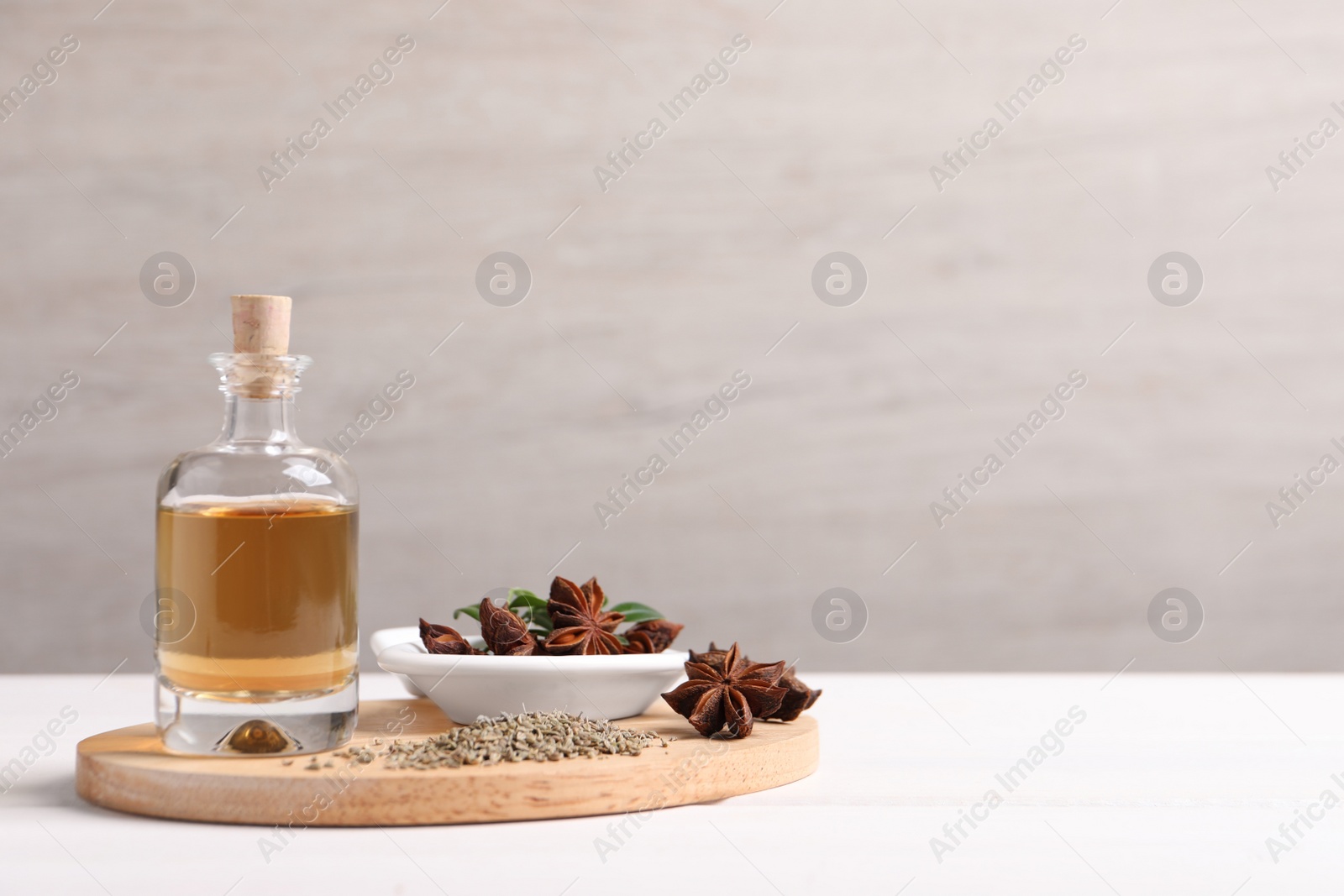 Photo of Anise essential oil and spice on white table, space for text