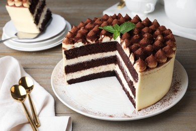 Delicious tiramisu cake with mint leaves on wooden table