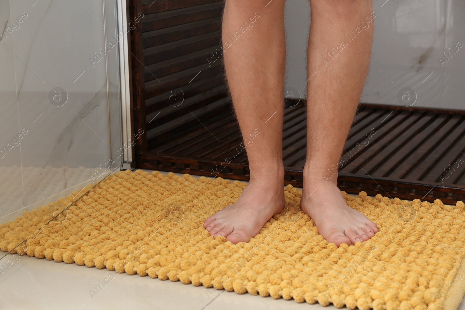 Photo of Man standing on soft mat near shower stall in bathroom, closeup