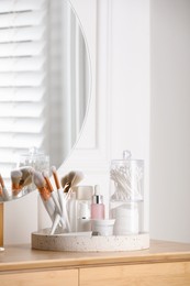 Containers with cotton swabs and pads near cosmetic products on dressing table. Space for text