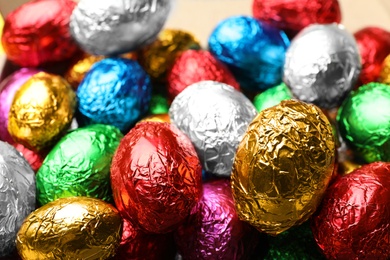 Photo of Chocolate eggs wrapped in colorful foil as background, closeup