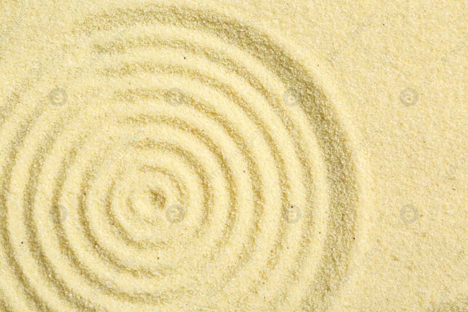 Photo of Zen rock garden. Circle pattern on beige sand, top view