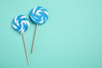 Sticks with bright lollipops on turquoise background, flat lay. Space for text