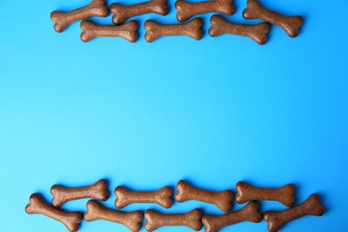 Bone shaped dog biscuits on light blue background, flat lay. Space for text