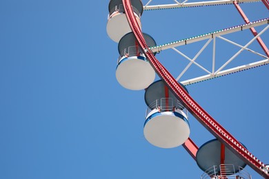 Photo of Beautiful large Ferris wheel against blue sky, low angle view