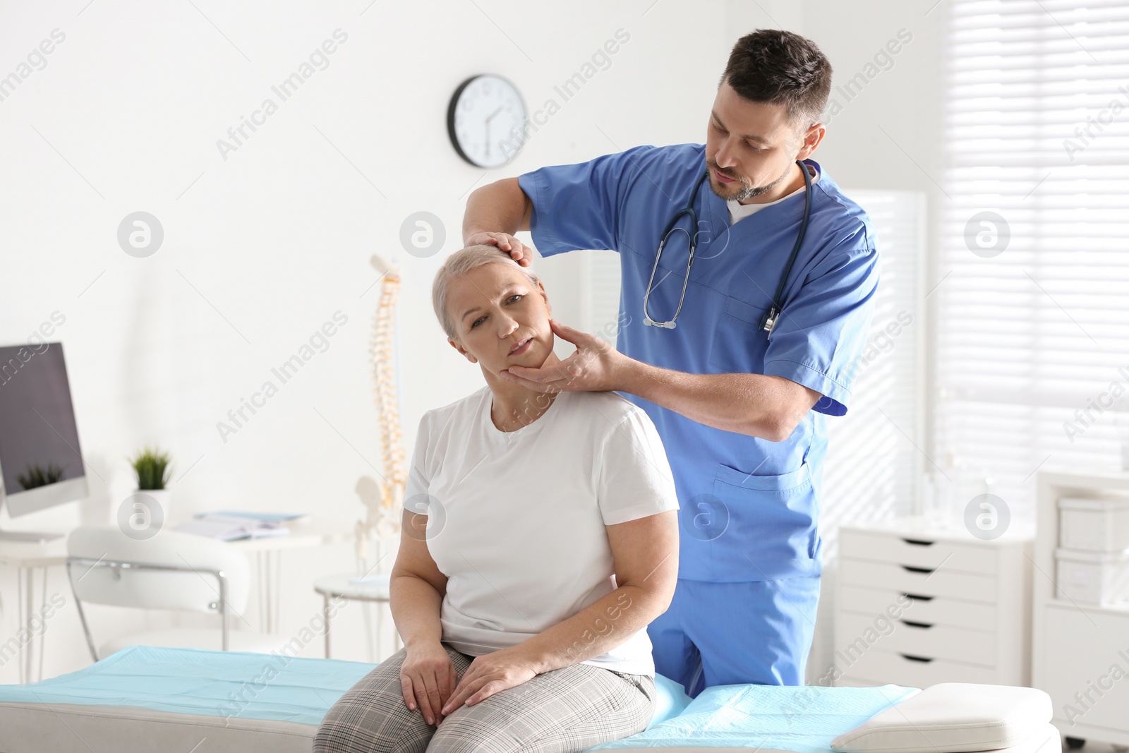 Photo of Male orthopedist examining patient with injured neck in clinic