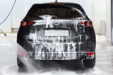 Photo of Washing auto with high pressure water jet at outdoor car wash