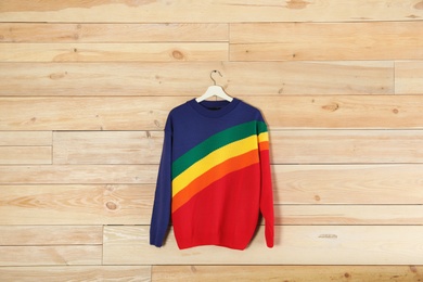 Hanger with stylish sweater on wooden background