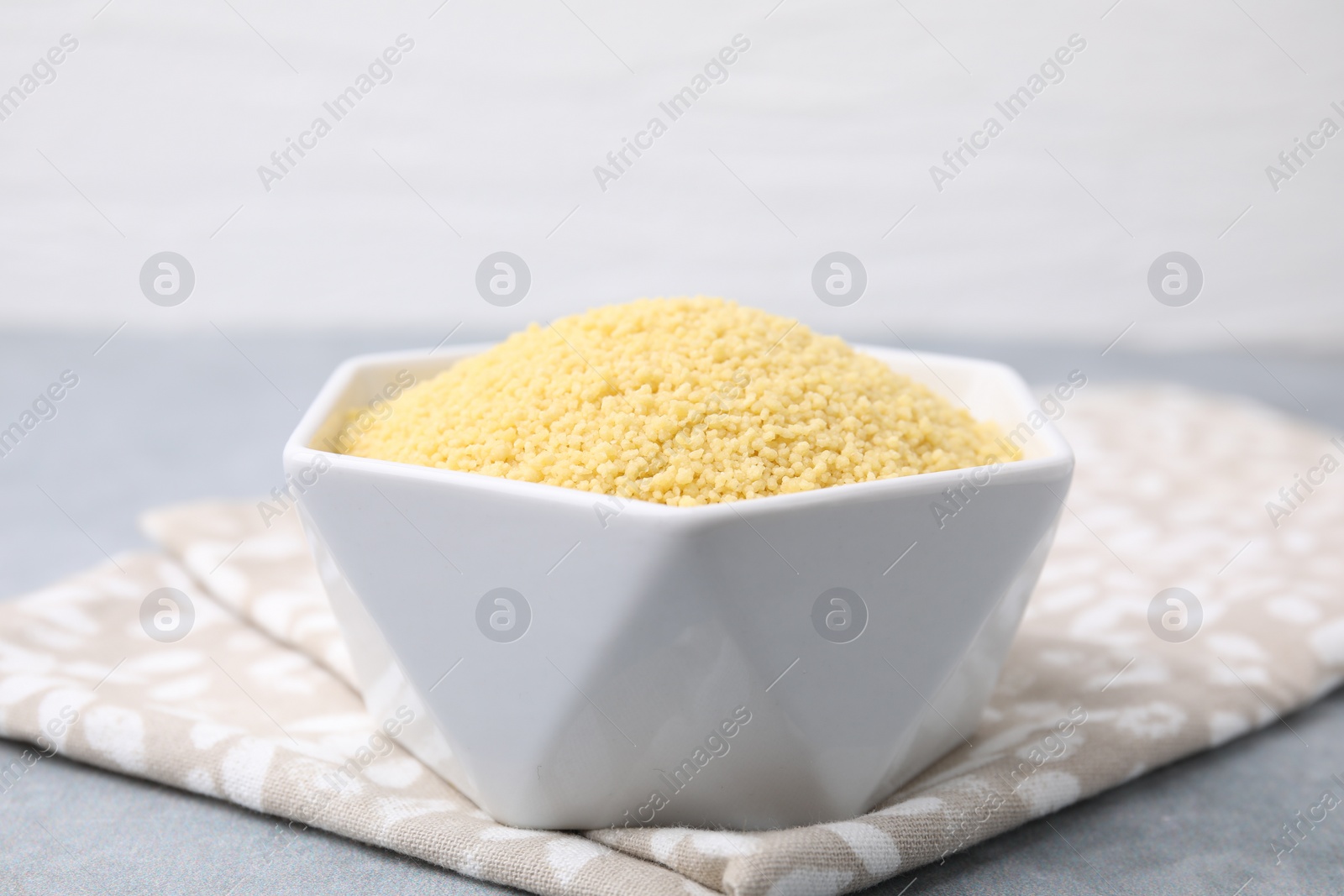 Photo of Raw couscous in bowl on table, closeup