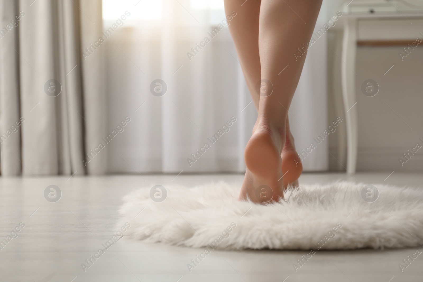 Photo of Woman standing on faux fur rug at home, closeup. Space for text