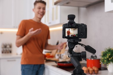 Food blogger recording video in kitchen, focus on camera