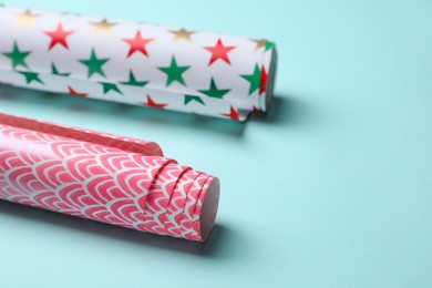 Photo of Different colorful wrapping paper rolls on turquoise background, closeup. Space for text